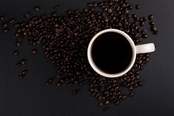 bir fincan kahve ve kahve çekirdekleri resmi.